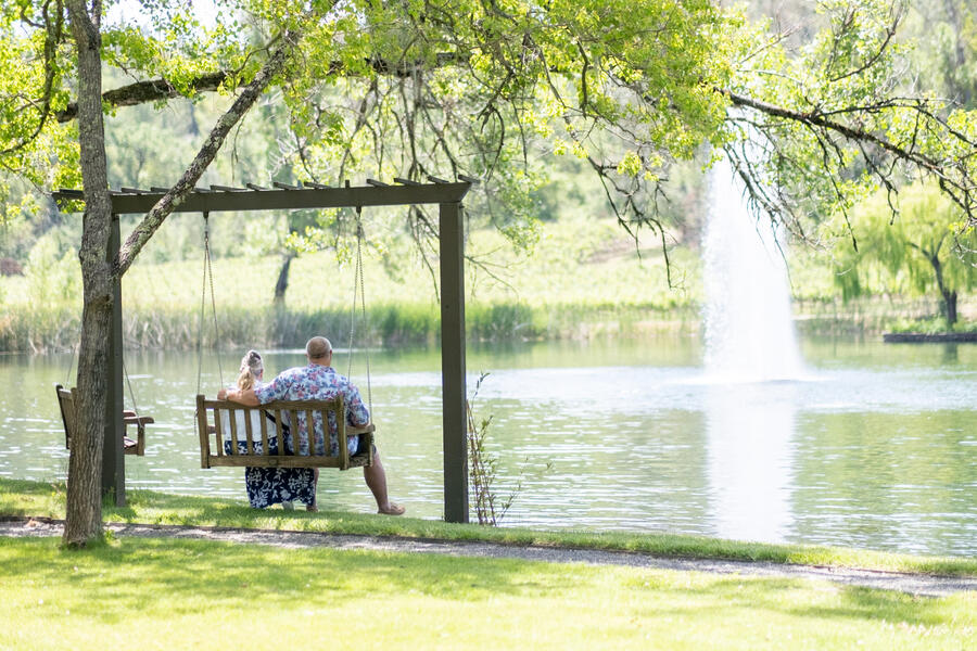 Couple relaxing on lakeside swing at Sinegal Estate, Napa Valley
